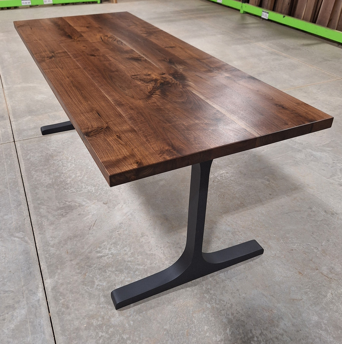 Full-length view of a solid walnut dining table on black metal legs