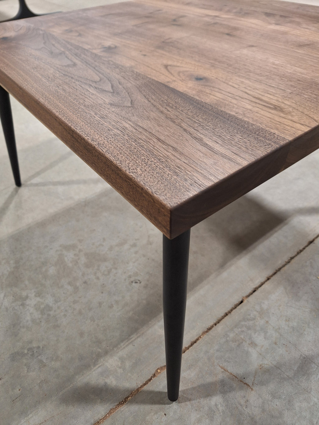 Corner detail of a walnut side table and black metal leg