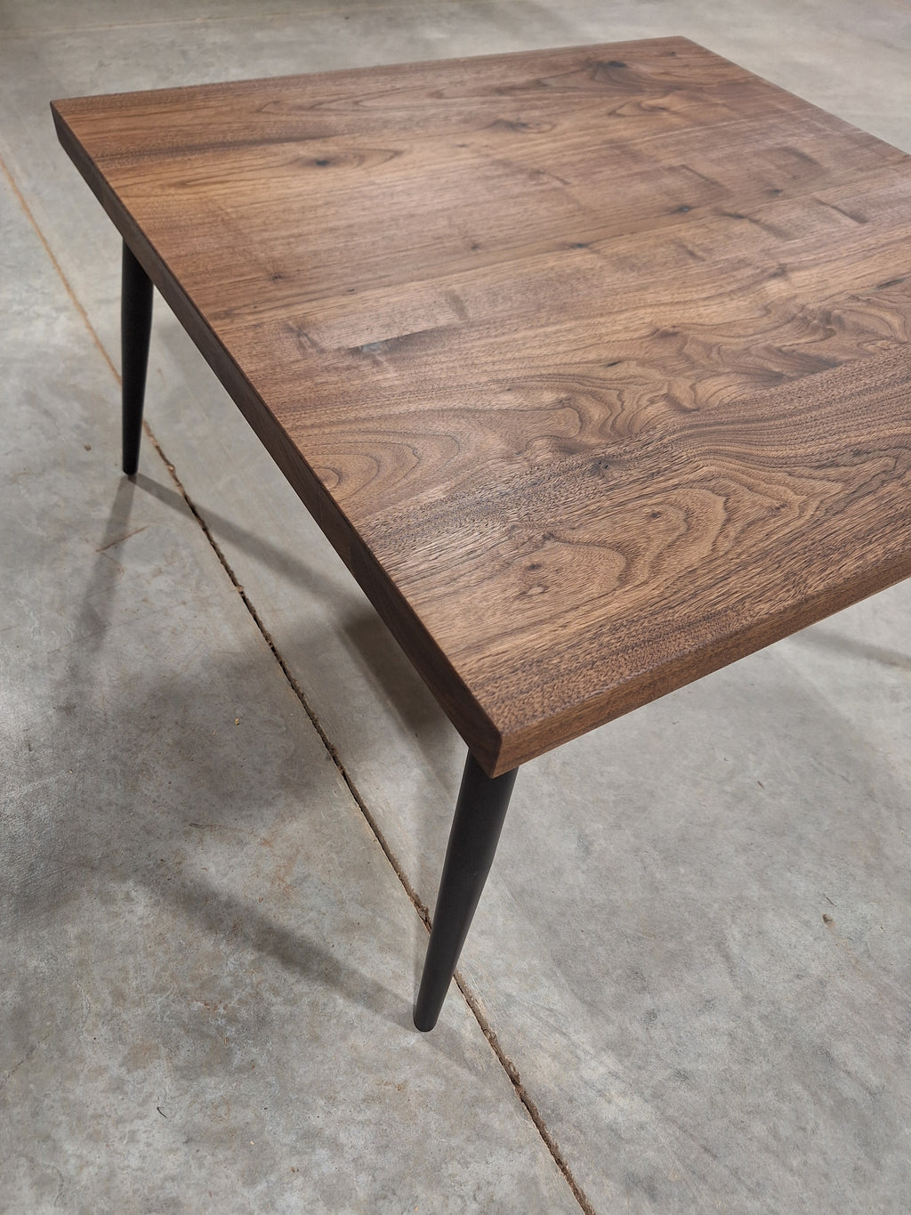 Solid walnut side table with black metal legs, angled view