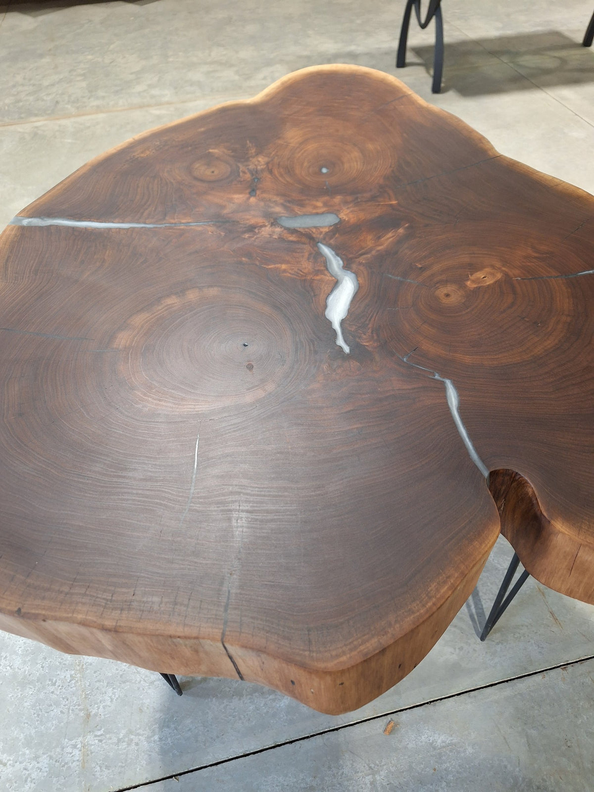Solid walnut live edge cookie table with white epoxy inlay and black hairpin legs, photographed in our Hiawatha shop (photo 3)